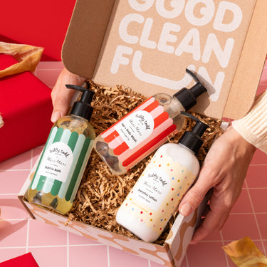Three bottles of the Winter Gift Set products in a box on a red and pink checkered background.